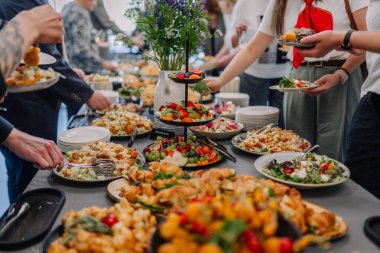 Valmiera, Letonya - 31 Mayıs 2025 - İnsanlar sosyal bir toplantı sırasında veya yemek servisi sırasında kendilerini salata, kruvasan ve taze meyvelerle dolu canlı bir büfe masasında buluyorlar..