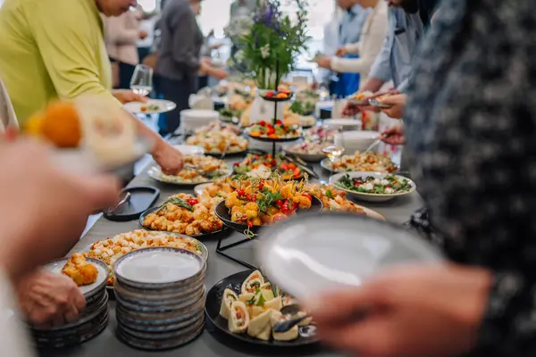 Valmiera, Letonya - 31 Mayıs 2025 - İnsanlar renkli mezeler, salatalar ve abur cuburlarla dolu bir açık büfe masasının etrafında toplanıyor..