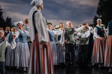 Valmiera, Letonya - 7 Haziran 2025 - Geleneksel Letonya kostümlü halk dansçıları GAUJA 80 kutlamaları sırasında sahnede senkronize bir şekilde gösteri yaptılar..