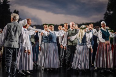 Valmiera, Letonya - 7 Haziran 2025 - Geleneksel Letonya kostümlü halk dansçıları GAUJA 80 kutlamaları sırasında sahnede senkronize bir şekilde gösteri yaptılar..