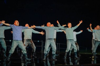 Valmiera, Letonya - 7 Haziran 2025 - GAUJA 80 'deki geleneksel Letonya halk dansları kolajı, renkli kostümlü dansçıları gece aydınlatmalı bir sahnede sergiliyorlar..