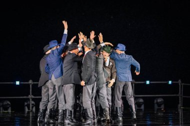 Valmiera, Letonya - 7 Haziran 2025 - GAUJA 80 'deki geleneksel Letonya halk dansları kolajı, renkli kostümlü dansçıları gece aydınlatmalı bir sahnede sergiliyorlar..