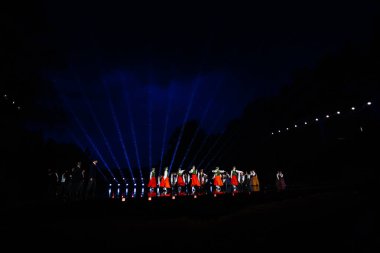 Valmiera, Letonya - 7 Haziran 2025 - GAUJA 80 'deki geleneksel Letonya halk dansları kolajı, renkli kostümlü dansçıları gece aydınlatmalı bir sahnede sergiliyorlar..