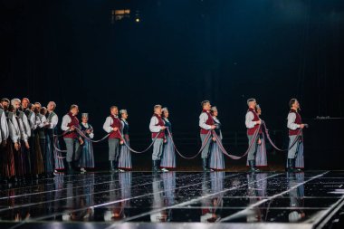 Valmiera, Letonya - 7 Haziran 2025 - GAUJA 80 'deki geleneksel Letonya halk dansları kolajı, renkli kostümlü dansçıları gece aydınlatmalı bir sahnede sergiliyorlar..