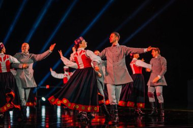 Valmiera, Letonya - 7 Haziran 2025 - GAUJA 80 'deki geleneksel Letonya halk dansları kolajı, renkli kostümlü dansçıları gece aydınlatmalı bir sahnede sergiliyorlar..