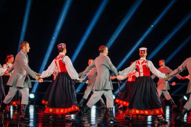 Valmiera, Letonya - 7 Haziran 2025 - GAUJA 80 'deki geleneksel Letonya halk dansları kolajı, renkli kostümlü dansçıları gece aydınlatmalı bir sahnede sergiliyorlar..