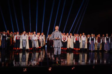 Valmiera, Letonya - 7 Haziran 2025 - GAUJA 80 'deki geleneksel Letonya halk dansları kolajı, renkli kostümlü dansçıları gece aydınlatmalı bir sahnede sergiliyorlar..