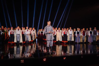 Valmiera, Letonya - 7 Haziran 2025 - GAUJA 80 'deki geleneksel Letonya halk dansları kolajı, renkli kostümlü dansçıları gece aydınlatmalı bir sahnede sergiliyorlar..