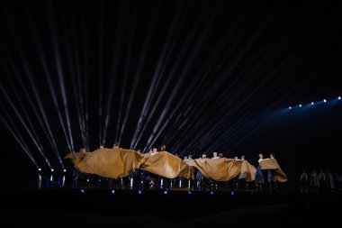 Valmiera, Letonya - 7 Haziran 2025 - GAUJA 80 'deki geleneksel Letonya halk dansları kolajı, renkli kostümlü dansçıları gece aydınlatmalı bir sahnede sergiliyorlar..