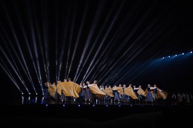 Valmiera, Letonya - 7 Haziran 2025 - GAUJA 80 'deki geleneksel Letonya halk dansları kolajı, renkli kostümlü dansçıları gece aydınlatmalı bir sahnede sergiliyorlar..