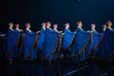 Valmiera, Letonya - 7 Haziran 2025 - GAUJA 80 'deki geleneksel Letonya halk dansları kolajı, renkli kostümlü dansçıları gece aydınlatmalı bir sahnede sergiliyorlar..