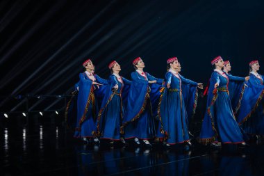 Valmiera, Letonya - 7 Haziran 2025 - GAUJA 80 'deki geleneksel Letonya halk dansları kolajı, renkli kostümlü dansçıları gece aydınlatmalı bir sahnede sergiliyorlar..