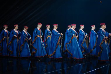 Valmiera, Letonya - 7 Haziran 2025 - GAUJA 80 'deki geleneksel Letonya halk dansları kolajı, renkli kostümlü dansçıları gece aydınlatmalı bir sahnede sergiliyorlar..