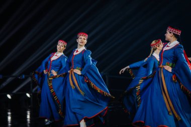 Valmiera, Letonya - 7 Haziran 2025 - GAUJA 80 'deki geleneksel Letonya halk dansları kolajı, renkli kostümlü dansçıları gece aydınlatmalı bir sahnede sergiliyorlar..