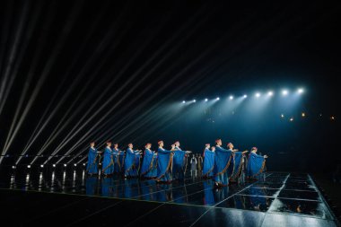 Valmiera, Letonya - 7 Haziran 2025 - GAUJA 80 'deki geleneksel Letonya halk dansları kolajı, renkli kostümlü dansçıları gece aydınlatmalı bir sahnede sergiliyorlar..