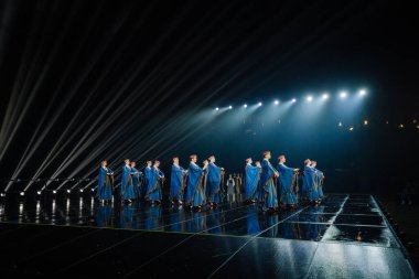 Valmiera, Letonya - 7 Haziran 2025 - GAUJA 80 'deki geleneksel Letonya halk dansları kolajı, renkli kostümlü dansçıları gece aydınlatmalı bir sahnede sergiliyorlar..