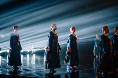 Valmiera, Letonya - 7 Haziran 2025 - GAUJA 80 'deki geleneksel Letonya halk dansları kolajı, renkli kostümlü dansçıları gece aydınlatmalı bir sahnede sergiliyorlar..