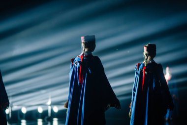 Valmiera, Letonya - 7 Haziran 2025 - GAUJA 80 'deki geleneksel Letonya halk dansları kolajı, renkli kostümlü dansçıları gece aydınlatmalı bir sahnede sergiliyorlar..