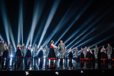 Valmiera, Letonya - 7 Haziran 2025 - GAUJA 80 'deki geleneksel Letonya halk dansları kolajı, renkli kostümlü dansçıları gece aydınlatmalı bir sahnede sergiliyorlar..