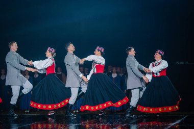 Valmiera, Letonya - 7 Haziran 2025 - GAUJA 80 'deki geleneksel Letonya halk dansları kolajı, renkli kostümlü dansçıları gece aydınlatmalı bir sahnede sergiliyorlar..