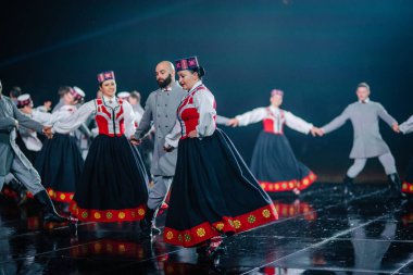Valmiera, Letonya - 7 Haziran 2025 - GAUJA 80 'deki geleneksel Letonya halk dansları kolajı, renkli kostümlü dansçıları gece aydınlatmalı bir sahnede sergiliyorlar..
