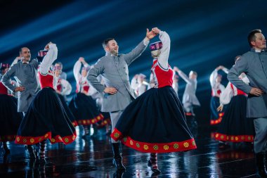 Valmiera, Letonya - 7 Haziran 2025 - GAUJA 80 'deki geleneksel Letonya halk dansları kolajı, renkli kostümlü dansçıları gece aydınlatmalı bir sahnede sergiliyorlar..