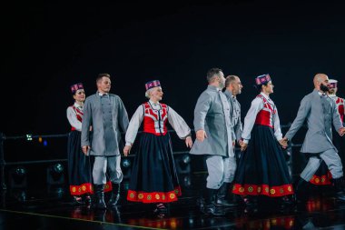 Valmiera, Letonya - 7 Haziran 2025 - GAUJA 80 'deki geleneksel Letonya halk dansları kolajı, renkli kostümlü dansçıları gece aydınlatmalı bir sahnede sergiliyorlar..