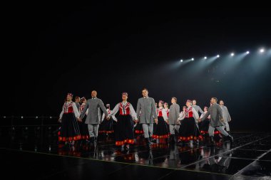 Valmiera, Letonya - 7 Haziran 2025 - GAUJA 80 'deki geleneksel Letonya halk dansları kolajı, renkli kostümlü dansçıları gece aydınlatmalı bir sahnede sergiliyorlar..