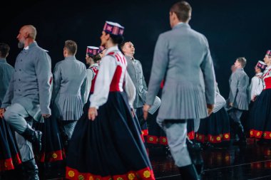 Valmiera, Letonya - 7 Haziran 2025 - GAUJA 80 'deki geleneksel Letonya halk dansları kolajı, renkli kostümlü dansçıları gece aydınlatmalı bir sahnede sergiliyorlar..