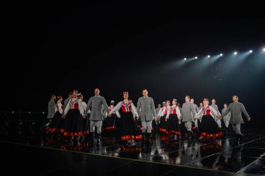 Valmiera, Letonya - 7 Haziran 2025 - GAUJA 80 'deki geleneksel Letonya halk dansları kolajı, renkli kostümlü dansçıları gece aydınlatmalı bir sahnede sergiliyorlar..