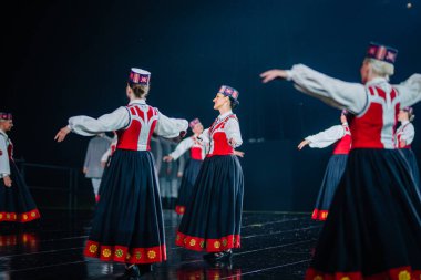 Valmiera, Letonya - 7 Haziran 2025 - GAUJA 80 'deki geleneksel Letonya halk dansları kolajı, renkli kostümlü dansçıları gece aydınlatmalı bir sahnede sergiliyorlar..