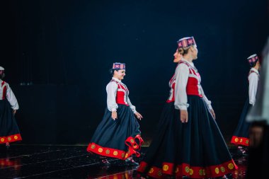 Valmiera, Letonya - 7 Haziran 2025 - GAUJA 80 'deki geleneksel Letonya halk dansları kolajı, renkli kostümlü dansçıları gece aydınlatmalı bir sahnede sergiliyorlar..