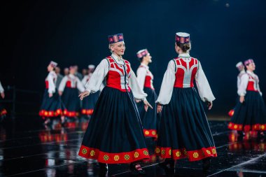 Valmiera, Letonya - 7 Haziran 2025 - GAUJA 80 'deki geleneksel Letonya halk dansları kolajı, renkli kostümlü dansçıları gece aydınlatmalı bir sahnede sergiliyorlar..
