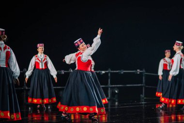 Valmiera, Letonya - 7 Haziran 2025 - GAUJA 80 'deki geleneksel Letonya halk dansları kolajı, renkli kostümlü dansçıları gece aydınlatmalı bir sahnede sergiliyorlar..