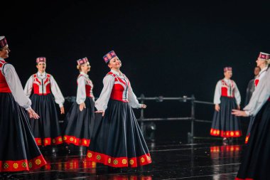 Valmiera, Letonya - 7 Haziran 2025 - GAUJA 80 'deki geleneksel Letonya halk dansları kolajı, renkli kostümlü dansçıları gece aydınlatmalı bir sahnede sergiliyorlar..