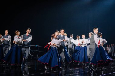 Valmiera, Letonya - 7 Haziran 2025 - GAUJA 80 'deki geleneksel Letonya halk dansları kolajı, renkli kostümlü dansçıları gece aydınlatmalı bir sahnede sergiliyorlar..