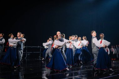 Valmiera, Letonya - 7 Haziran 2025 - GAUJA 80 'deki geleneksel Letonya halk dansları kolajı, renkli kostümlü dansçıları gece aydınlatmalı bir sahnede sergiliyorlar..