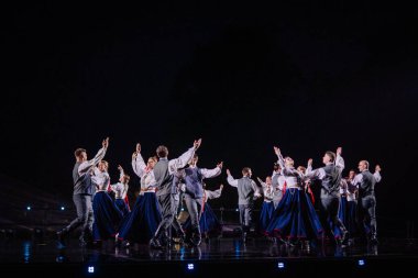 Valmiera, Letonya - 7 Haziran 2025 - GAUJA 80 'deki geleneksel Letonya halk dansları kolajı, renkli kostümlü dansçıları gece aydınlatmalı bir sahnede sergiliyorlar..