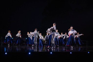 Valmiera, Letonya - 7 Haziran 2025 - GAUJA 80 'deki geleneksel Letonya halk dansları kolajı, renkli kostümlü dansçıları gece aydınlatmalı bir sahnede sergiliyorlar..