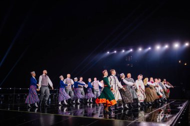 Valmiera, Letonya - 7 Haziran 2025 - GAUJA 80 'deki geleneksel Letonya halk dansları kolajı, renkli kostümlü dansçıları gece aydınlatmalı bir sahnede sergiliyorlar..
