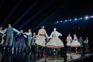 Valmiera, Letonya - 7 Haziran 2025 - GAUJA 80 'deki geleneksel Letonya halk dansları kolajı, renkli kostümlü dansçıları gece aydınlatmalı bir sahnede sergiliyorlar..