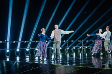 Valmiera, Letonya - 7 Haziran 2025 - GAUJA 80 'deki geleneksel Letonya halk dansları kolajı, renkli kostümlü dansçıları gece aydınlatmalı bir sahnede sergiliyorlar..