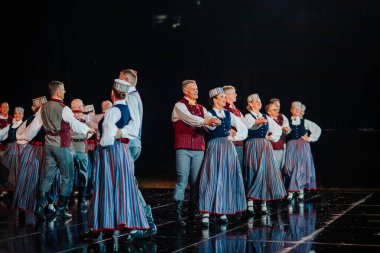 Valmiera, Letonya - 7 Haziran 2025 - GAUJA 80 'deki geleneksel Letonya halk dansları kolajı, renkli kostümlü dansçıları gece aydınlatmalı bir sahnede sergiliyorlar..