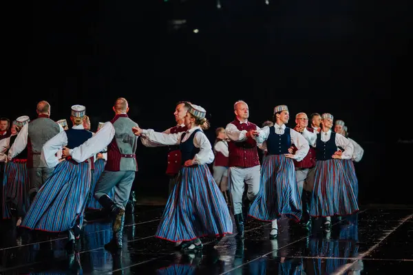 Valmiera, Letonya - 7 Haziran 2025 - GAUJA 80 'deki geleneksel Letonya halk dansları kolajı, renkli kostümlü dansçıları gece aydınlatmalı bir sahnede sergiliyorlar..