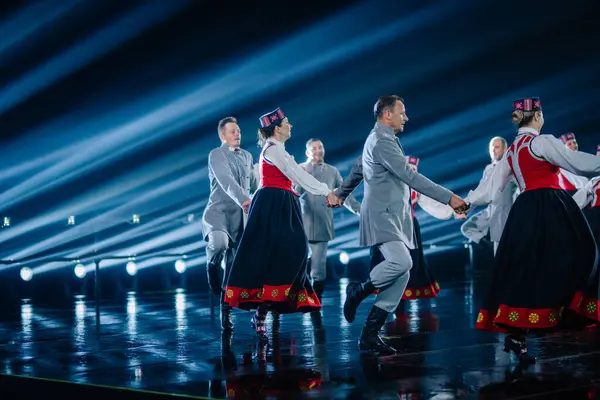 Valmiera, Letonya - 7 Haziran 2025 - GAUJA 80 'deki geleneksel Letonya halk dansları kolajı, renkli kostümlü dansçıları gece aydınlatmalı bir sahnede sergiliyorlar..