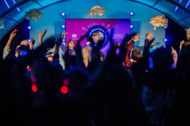 Cesis, Letonya - 20 Haziran 2025 - İnsanlar renkli sahne ışıkları altında, İngiliz Sessiz Diskosu 'nu gece gösteren bir DJ ile sessiz bir disko etkinliğinde ellerini kaldırıyorlar.