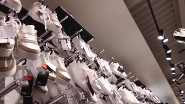 Valmiera, Letonya - 8 Temmuz 2025 - Bir perakende mağazasının ayakkabı rafında sergilenen beyaz spor ayakkabıları, etiketleri ve fiyat etiketleri mağaza ışıkları altında açıkça görülebiliyor.