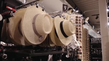 Valmiera, Letonya - 8 Temmuz 2025 - Güneş gözlüğü ve aksesuar raflarının yanında dekoratif bantlı hasır şapkalar sergileniyor. Yaz temalı alışveriş sahnesi.