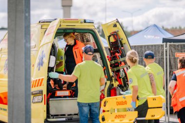 Valmiera, Letonya - 7 Temmuz 2025 - Paramedikler dışarıda acil bir durumda bir hastayı ambulansa yüklediler. Sağlık personeli kurtarma ekipmanlarıyla hızlı çalışır..
