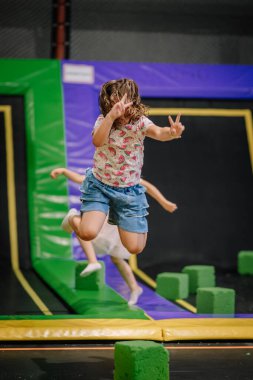Havanın ortasında, neşeli bir yıldızın içinde, kapalı bir oyun merkezinde trambolinde, karpuz desenli tişört ve kot şortla atlayan genç bir kız..